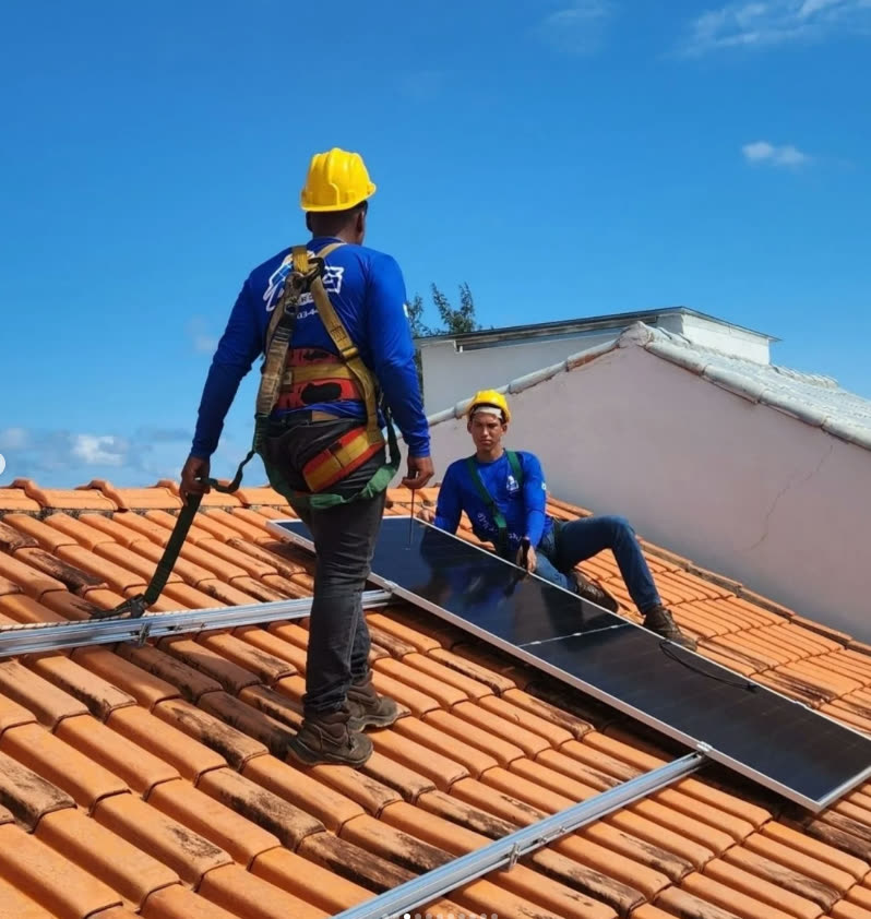 Instaladores da ASG Energia, com capacete e cinto de segurança, no telhado