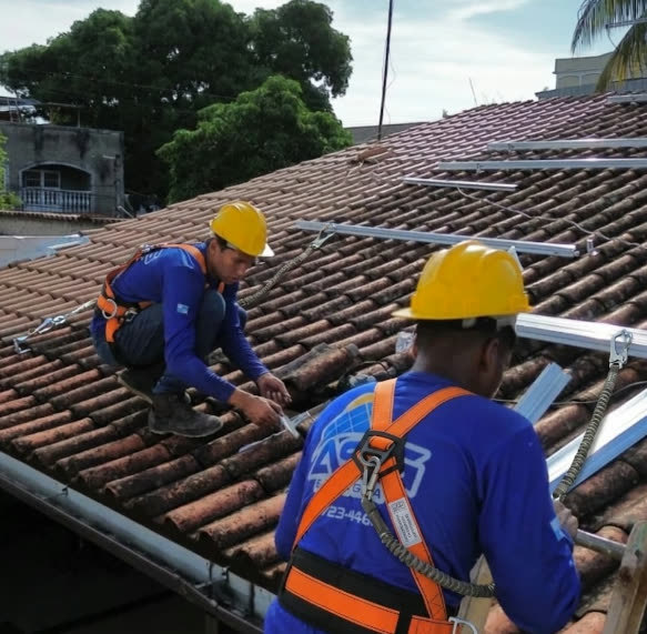 Instaladores da ASG Energia, com capacete e cinto de segurança, no telhado